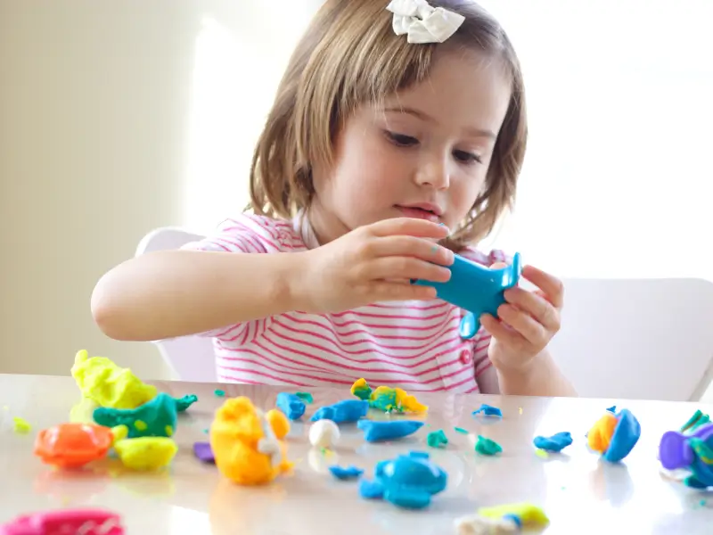 Child doing fine motor coordination activity with play modeling clay